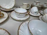 a lot of white and gold plates and cups and saucers