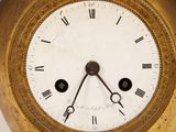 a gold clock with roman numerals on the face