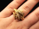 a woman ' s hand holding a gold ring with diamonds on it