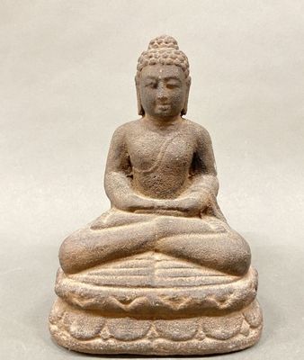 statue of a seated buddha on a rock with a white background