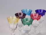 several different colored wine glasses are lined up on a white surface