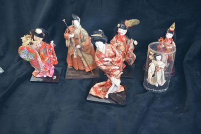 five figurines of asian women in kimono robes are displayed on a black background