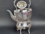 a silver tea pot with a wooden handle on a stand