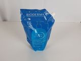 Nettoyant pour le visage Bioderma dans un sac bleu posé sur une surface blanche