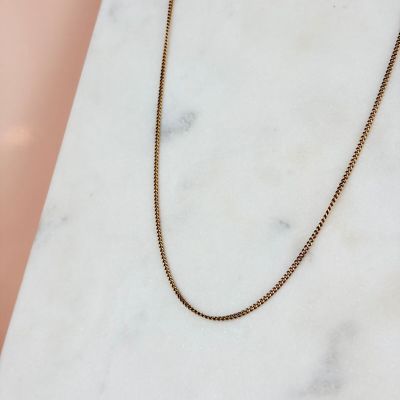 un collier à chaîne en or posé sur une surface en marbre