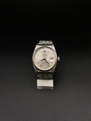 une image représentant une montre argentée posée sur une surface noire