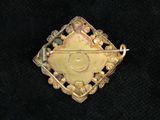 a close up of a gold pendant with a diamond on it