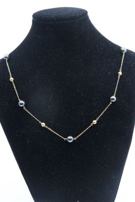 un collier de mannequin noir orné de perles et de perles dorées