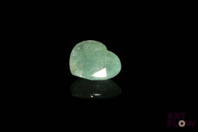 a close up of a green heart shaped stone on a black surface