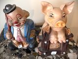 deux figurines représentant un cochon et un homme assis sur une chaise