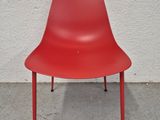 une chaise rouge posée sur un sol en béton