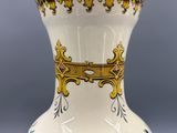 un vase blanc orné d'une bordure dorée et d'une couronne