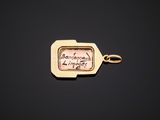 a close up of a gold keychain with a picture of a person on it