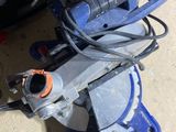 a blue circular saw sitting on the floor next to a black bag