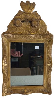 a mirror with a gold frame and a hand in the mirror