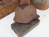 a rusty helmet sitting on top of a piece of wood