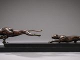 two bronze statues of a dog and a cat running on a black base