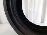 a close up of a tire on a white surface with a white curtain in the background