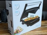 emballage d'un appareil à sandwich posé sur une table en bois devant un mixeur