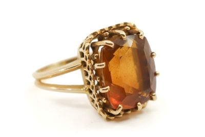 un gros plan d'une bague en or sertie d'une grosse pierre brune