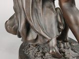 bronze statue of a woman holding a basket of flowers on top of a table