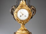 une horloge en or posée sur un socle, surmontée d'un oiseau