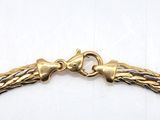 a close up of a gold bracelet on a white surface