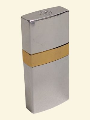 briquet argenté orné d'une bande dorée sur fond blanc