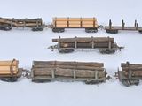 six wagons en bois chargés de grumes, posés sur une surface blanche