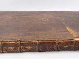 an old book sitting on top of a white table next to a white wall