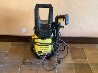un nettoyeur haute pression jaune et noir posé par terre