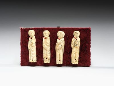 trois figurines en ivoire représentant un homme et une femme, posées sur du velours rouge