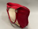 a red and white handbag sitting on top of a white table