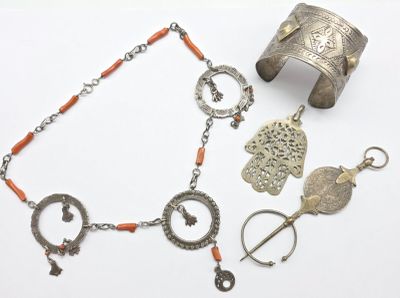 un bracelet en argent, un bracelet et d'autres bijoux posés sur une surface blanche