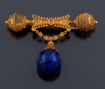 une image représentant une broche en or et en lapis-lazuli sur un fond noir