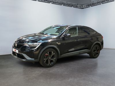 La voiture noire est garée dans une grande pièce aux murs blancs.