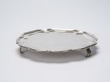 a silver plate on a stand on a white surface