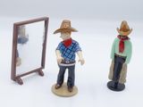 two figurines of a man and a woman standing in front of a mirror