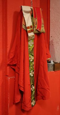 a red coat hanging on a red wall next to a toilet