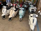 Plusieurs scooters sont alignés les uns à côté des autres dans un garage