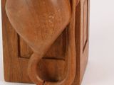a wooden vase with a cat in it on a shelf