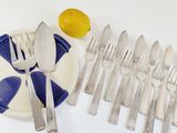 a plate with a bunch of silverware on it next to a lemon