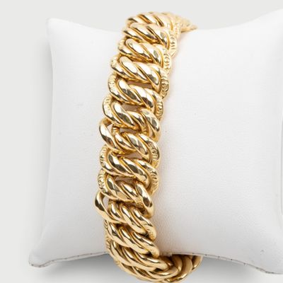 gros plan d'un bracelet en chaîne en or sur un oreiller