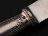 a silver knife with a silver handle on a black surface