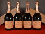 four bottles of champagne are lined up on a red table