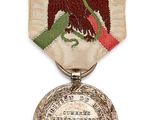 an old silver medal with a red flower on a white background