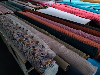 many rolls of fabric sitting on a rack in a room
