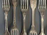 six forks and spoons are lined up on a gray surface