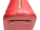 the red purse is sitting on a white surface with a white background