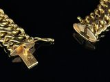 two gold chains with a key attached to them on a black surface